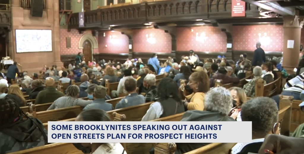 Screenshot of a news story showing the pews of a church filled with community members.